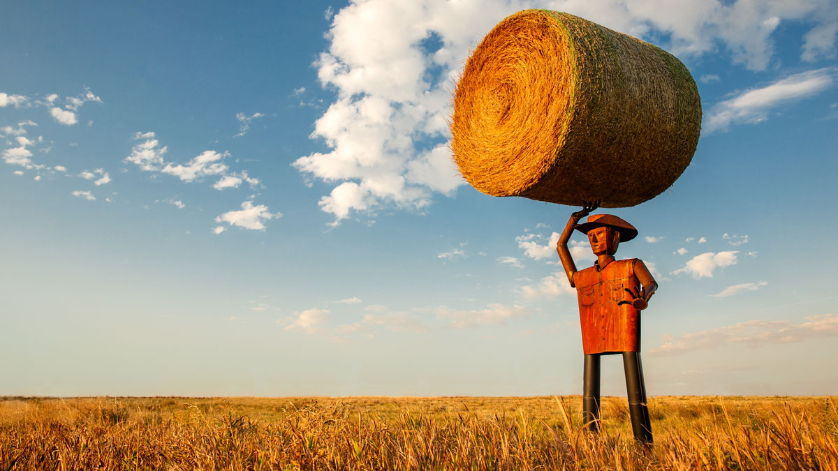 metal cowboy holding round hay bale with one hand, photo by Todd Klassy