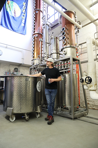 Montgomery Distillery owner Ryan, standing by cooking whiskey casket.png